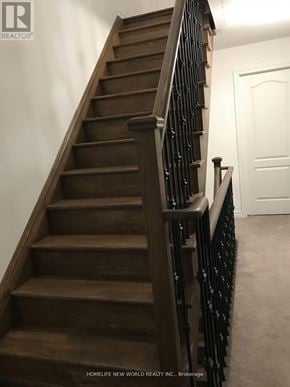 Oshawa (Windfields) townhouse for rent - A staircase with a wooden handrail and a white door at the top.
