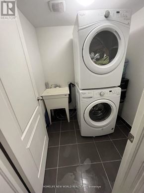 Oshawa (Windfields) townhouse for rent - A small laundry room with a washer and dryer stacked on top of each other.