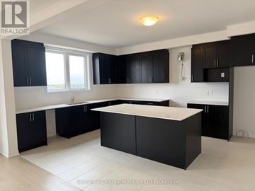 South-West Oxford apartment for rent - A kitchen with black cabinets and a white island.