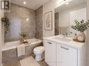 Toronto (Moss Park) condo for rent - A bathroom with a white toilet, sink, and a plant.