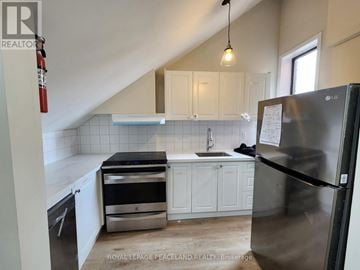 Toronto (University) multi-family for rent - A kitchen with a stainless steel refrigerator and white cabinets.