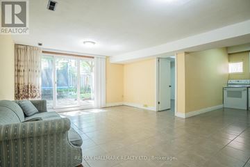 Toronto (Bedford Park-Nortown) apartment for rent - A living room with a grey couch and a sliding glass door leading to a balcony.