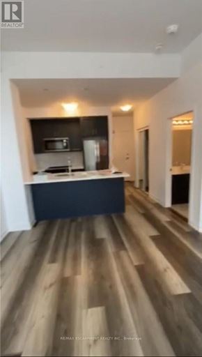Hamilton (Waterdown) condo for rent - A modern kitchen with wooden flooring and a dark countertop.