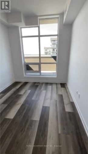 Hamilton (Waterdown) condo for rent - A room with wooden floors and a window overlooking a balcony.