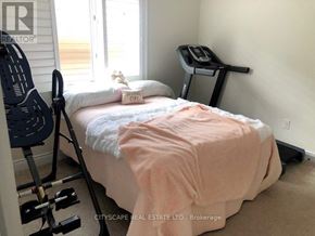 Niagara Falls (Brown) apartment for rent - A bedroom with a bed, a chair, and a treadmill.