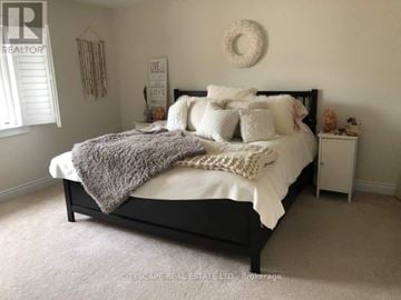 Niagara Falls (Brown) apartment for rent - A bedroom with a large bed and a wreath on the wall.