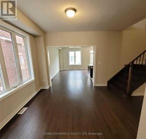 Brampton (Northwest Brampton) townhouse for rent - A spacious room with wooden floors and a staircase.