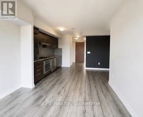 Toronto (Agincourt South-Malvern West) condo for rent - A spacious room with wooden flooring and a kitchen area in the background.