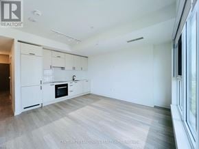 Toronto (Banbury-Don Mills) condo for rent - A spacious, empty room with a kitchen area to the left and a large window with a view of the city.