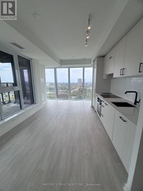 Toronto (Banbury-Don Mills) condo for rent - A modern kitchen with white cabinets and a view of the city.