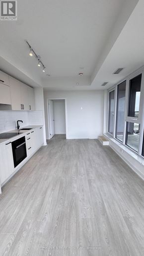 Toronto (Banbury-Don Mills) condo for rent - A spacious kitchen with white cabinets and a grey floor.