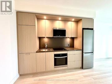 Toronto (Islington-City Centre West) condo for rent - A modern kitchen with wooden cabinets and stainless steel appliances.