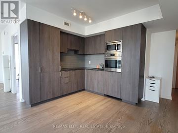 Toronto (Bay Street Corridor) condo for rent - A modern kitchen with dark wood cabinets and stainless steel appliances.