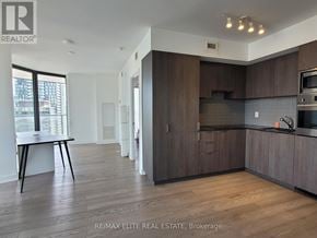 Toronto (Bay Street Corridor) condo for rent - A modern kitchen with dark wood cabinets and a white island.