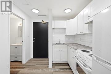 London East (East F) multi-family for rent - A white kitchen with a black door and a stove top oven.