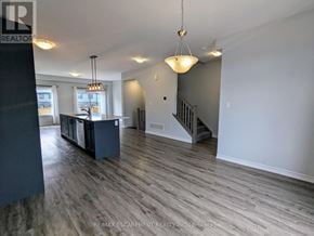 Hamilton (Mountview) townhouse for rent - A spacious room with wood flooring and a staircase in the background.