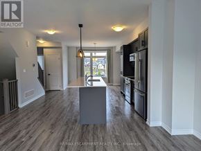 Hamilton (Mountview) townhouse for rent - A kitchen with a black fridge and stove, a dining table with chairs, and a view of the backyard through the window.