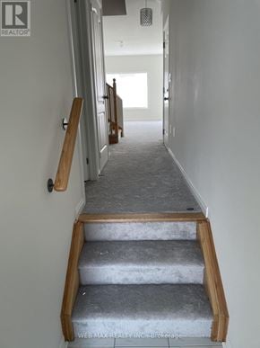 Oshawa (Windfields) townhouse for rent - A hallway with a staircase leading to a door.