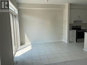 Oshawa (Windfields) townhouse for rent - A white room with a kitchen area in the background.