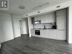 Toronto (Dovercourt-Wallace Emerson-Junction) condo for rent - A modern kitchen with white cabinets and a wooden floor.