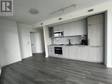 Toronto (Dovercourt-Wallace Emerson-Junction) condo for rent - A modern kitchen with white cabinets and a wooden floor.