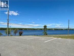Miramichi apartment for rent - A parking lot with a lake in the background and a realtor logo in the corner.