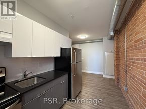 Toronto (Junction Area) condo for rent - A kitchen with black countertops and a stainless steel refrigerator.