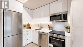 Toronto (Moss Park) condo for rent - A modern kitchen with a stainless steel refrigerator, microwave, and oven.