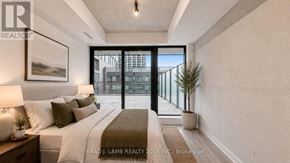 Toronto (Moss Park) condo for rent - A well-lit bedroom with a large bed and a view of the city through the glass door.