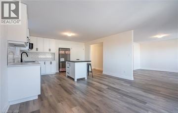 Beamsville apartment for rent - A spacious kitchen with white cabinets and a wooden floor.