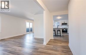 Beamsville apartment for rent - A spacious room with wooden flooring and a kitchen area in the background.