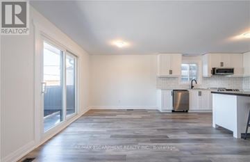 Lincoln (Beamsville) apartment for rent - A spacious kitchen with white cabinets and a stainless steel refrigerator.