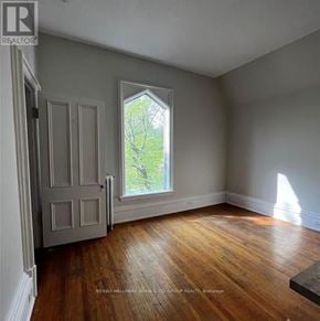Brockville multi-family for rent - A room with a wooden floor and a window with a view of trees.
