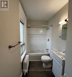 Brockville multi-family for rent - A white bathroom with a toilet, sink, and bathtub.