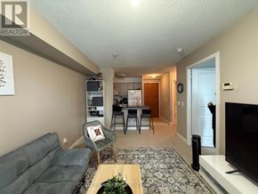 Toronto (Willowdale East) condo for rent - A living room with a grey sofa, a coffee table, and a television.
