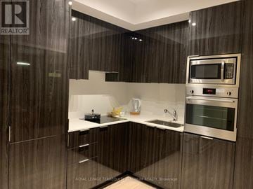 Toronto (Bay Street Corridor) condo for rent - A modern kitchen with a microwave and oven built into the cabinetry.