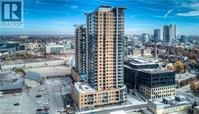 Kitchener condo for rent - A tall residential building is the centerpiece of a cityscape.