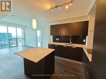 Toronto (Lansing-Westgate) condo for rent - A modern kitchen with dark brown cabinets and a large island.