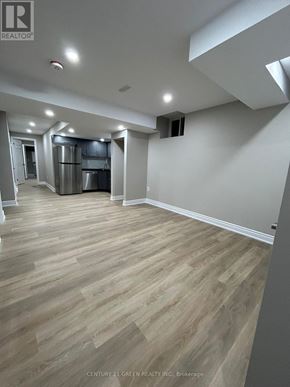 Oshawa (Kedron) apartment for rent - A spacious room with wooden flooring and white walls.