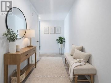Burlington (Brant) condo for rent - A well-lit, minimalist living room with a sofa, a table with a lamp, and a mirror.