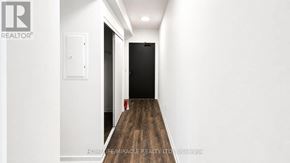 Burlington (Alton) condo for rent - A hallway with a wooden floor leading to a black door.