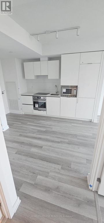 Toronto (Kensington-Chinatown) condo for rent - A kitchen with white cabinets and a grey floor.