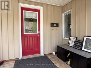 Niagara Falls (Hospital) apartment for rent - A red door with a glass window is on the left and a black shelf with two framed signs is on the right.