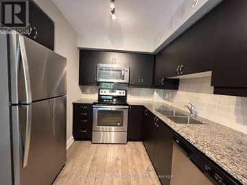 Whitchurch-Stouffville (Stouffville) condo for rent - A kitchen with black cabinets and a stainless steel refrigerator.