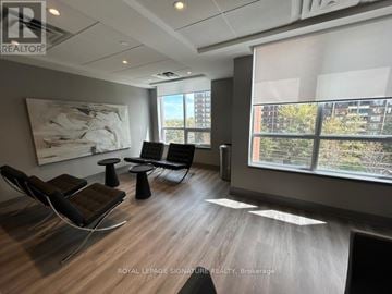 Toronto (Tam O'shanter-Sullivan) condo for rent - A modern living room with a large painting on the wall and a view of the outside through the windows.