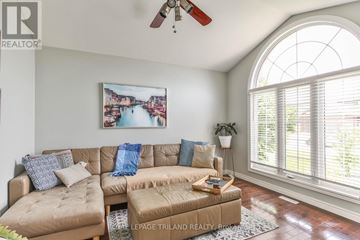 Central Elgin apartment for rent - A living room with a large window and a painting of a cityscape on the wall.