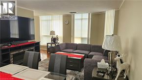 Kitchener condo for rent - A living room with a grey couch, a red table, and a television.