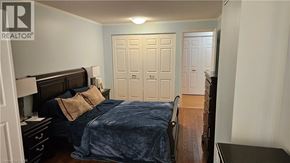 Kitchener condo for rent - A bedroom with a bed, nightstand, and two doors.