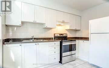 Toronto (Morningside) townhouse for rent - A kitchen with white cabinets and a black stove top oven.