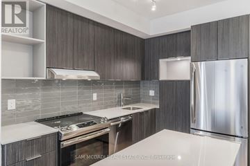 Mississauga (Central Erin Mills) condo for rent - A modern kitchen with dark wood cabinets and stainless steel appliances.